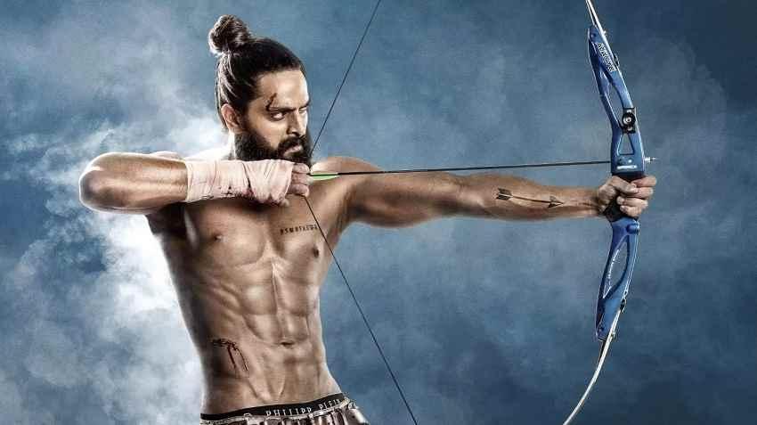 تصویر از صحنه‌ای هیجان‌انگیز از فیلم "هدف"، که در آن شخصیت اصلی در حال تیراندازی و آمادگی برای نبرد است. این فیلم جنگی هندی داستان یک سرباز را روایت می‌کند که با چالش‌های بزرگ روبرو شده و به دنبال دستیابی به هدفی مهم است. 